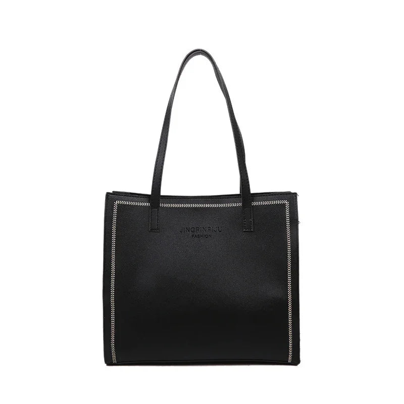 Black leather tote bag with double handles and decorative white stitching, minimalist fashion design
