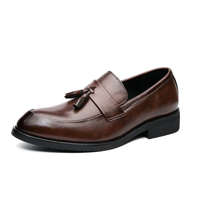 Brown leather men's tassel loafer with black sole and low heel on white background