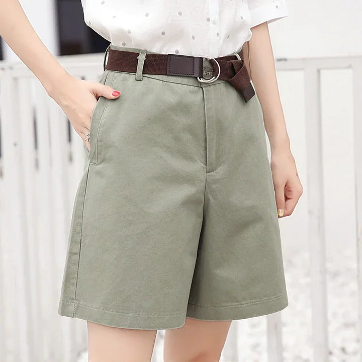 woman wearing olive green high-waist shorts with brown belt and white polka dot blouse
