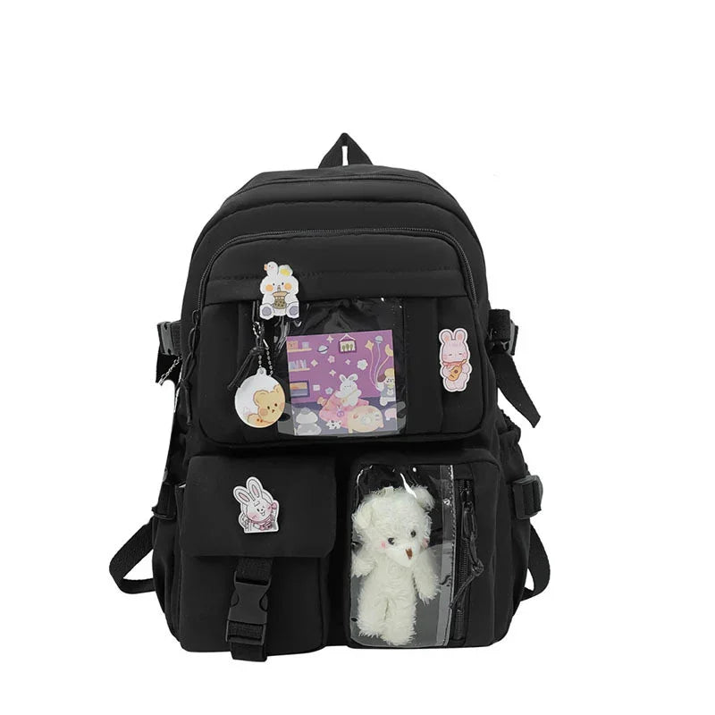 Black backpack decorated with cute animal pins, clear pocket showing white plush toy, and cartoon card