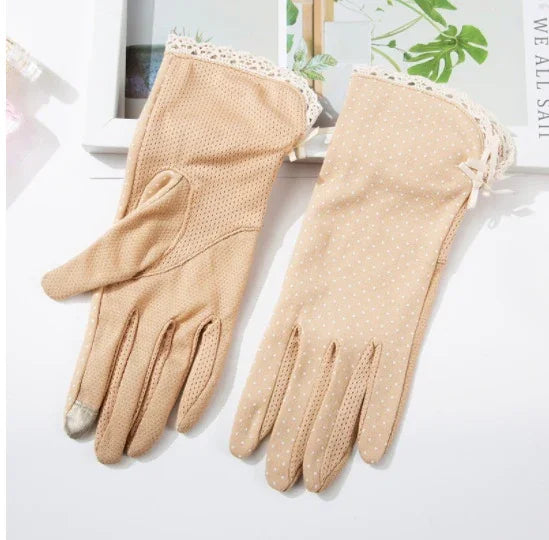 Pair of beige women's gloves with lace trim and polka dot and mesh patterns on white surface