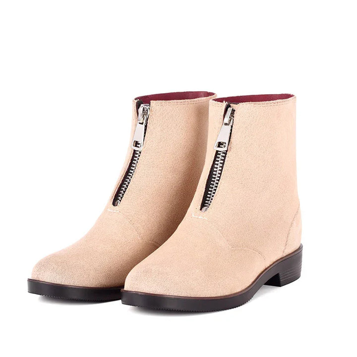 Beige suede ankle boots with front silver zipper and black low block heel on white background