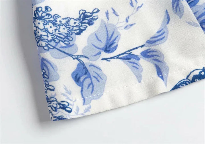 Close-up of white fabric with blue floral leaf pattern and stitched hem detail