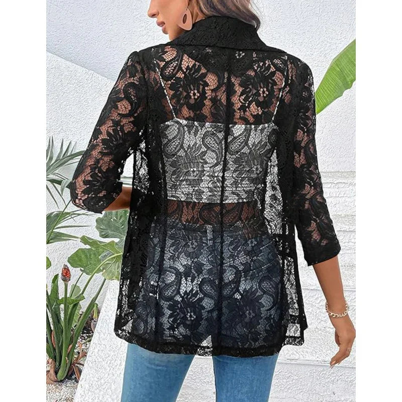 Woman wearing black floral lace blazer with three-quarter sleeves over jeans against white wall