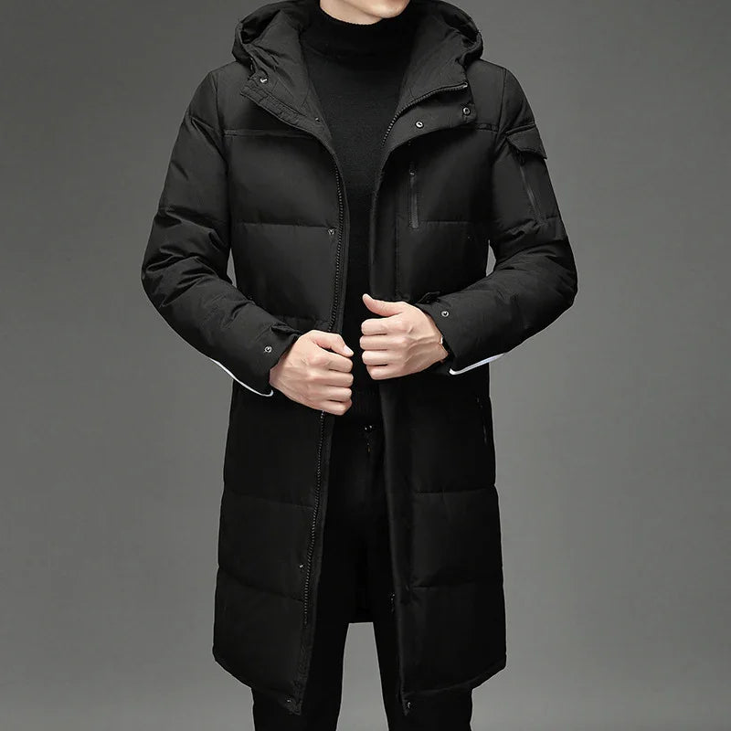 Man wearing black long puffer coat with hood and zippered pockets on gray background