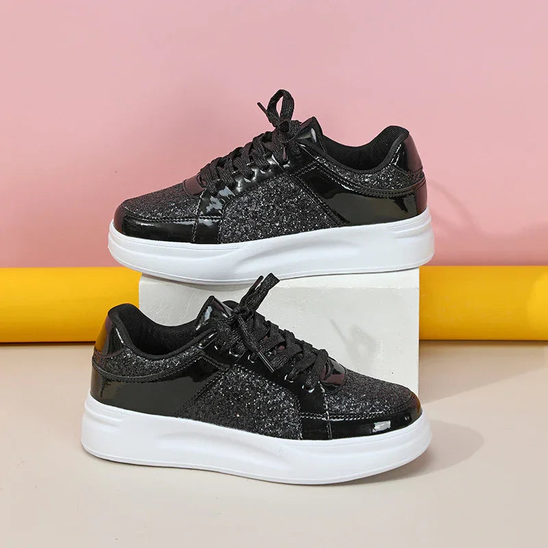 Black glitter and patent leather sneakers with white soles on white block, pink and yellow background