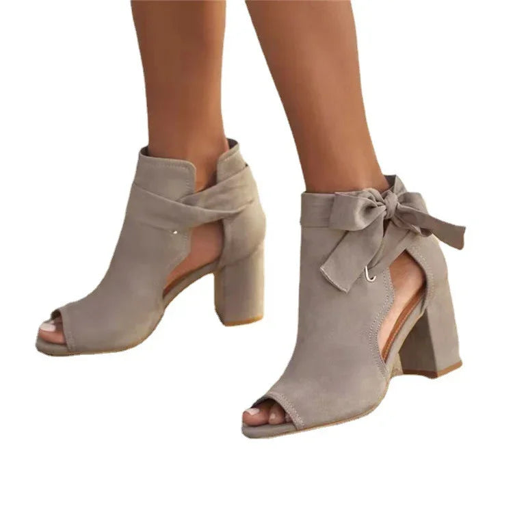 Beige suede peep-toe ankle boots with block heels and tied bow detail on white background