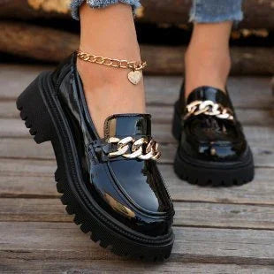 Black patent leather chunky loafers with gold chain detail worn with gold heart charm anklet