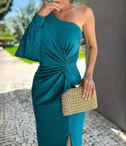 Woman wearing teal one-shoulder midi dress with knotted waist and holding gold textured clutch