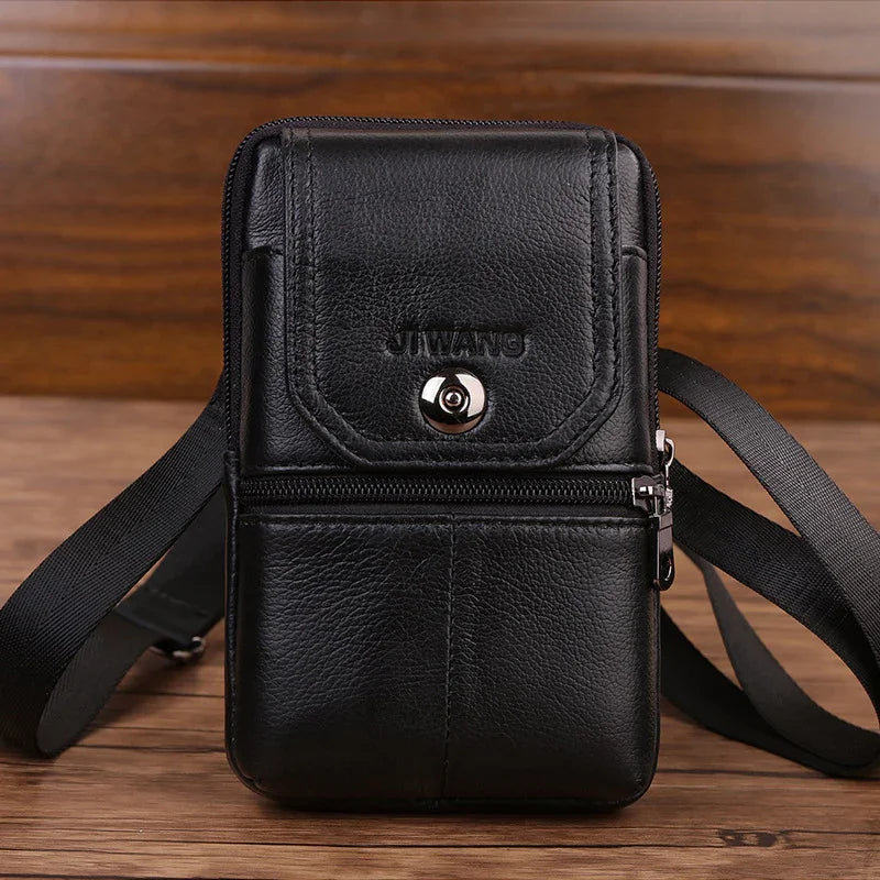 Black leather crossbody bag with zipper and button closure on wooden surface