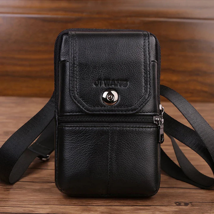 Black leather crossbody bag with zipper and button closure on wooden surface