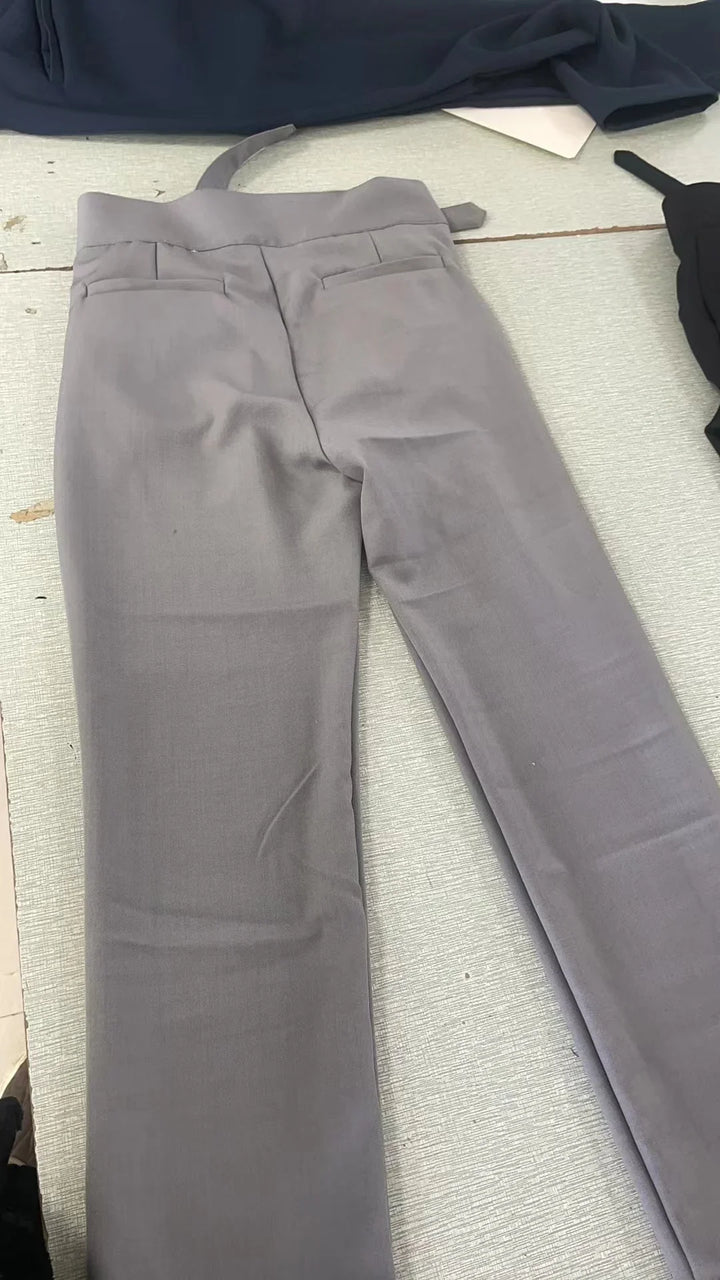 Light gray formal trousers with belt loops and back pockets laid flat on a textured surface