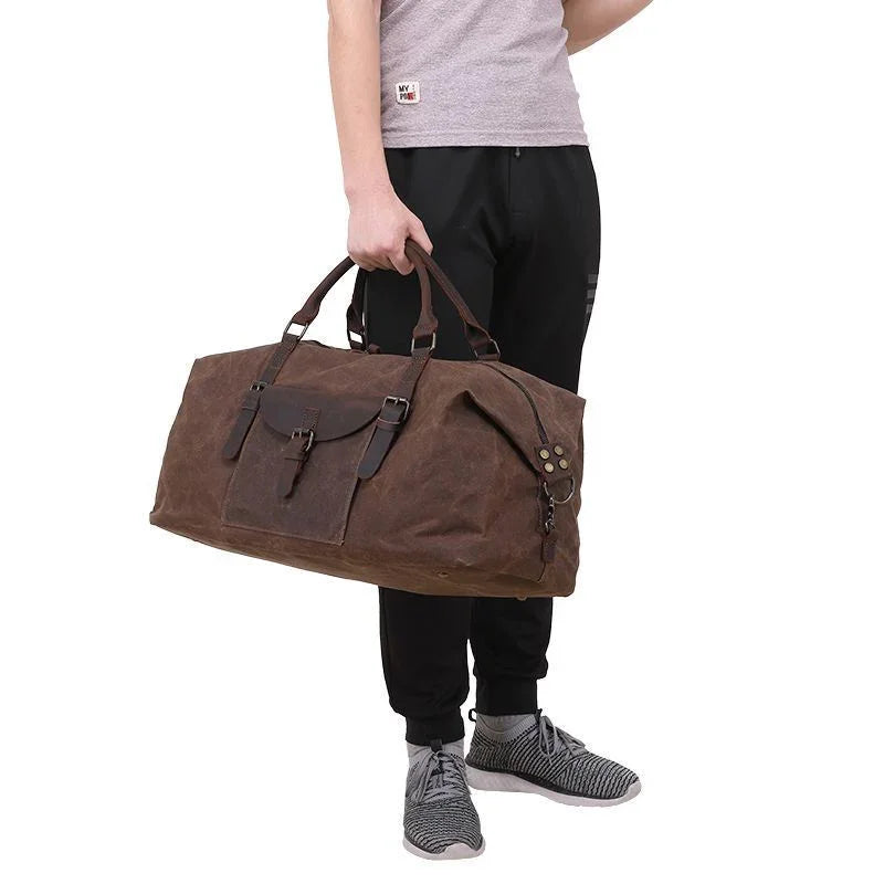 Man holding large brown leather travel bag with buckle and front pocket, casual outfit
