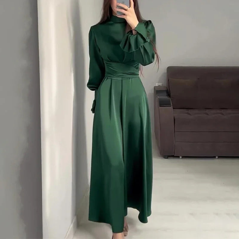 Woman wearing elegant dark green satin long dress with high neck and puffed sleeves taking mirror selfie indoors