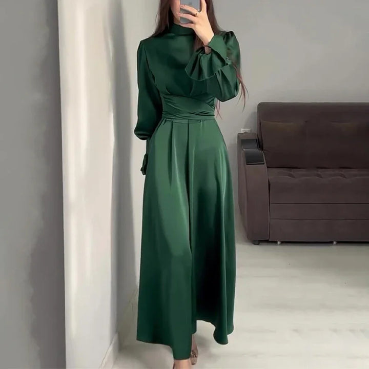 Woman wearing elegant dark green satin long dress with high neck and puffed sleeves taking mirror selfie indoors