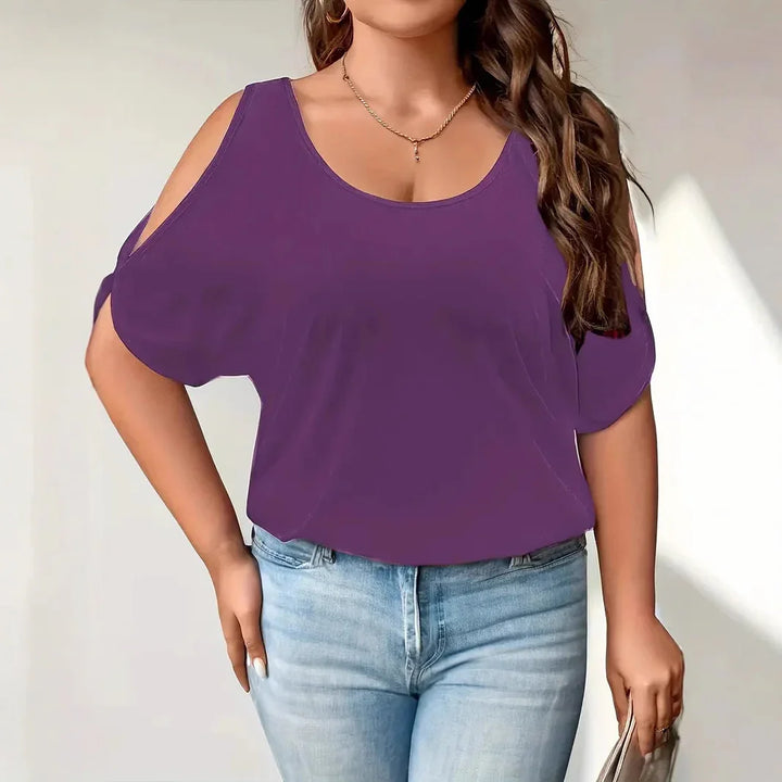 Woman wearing purple cold shoulder top paired with light blue jeans holding a gray clutch