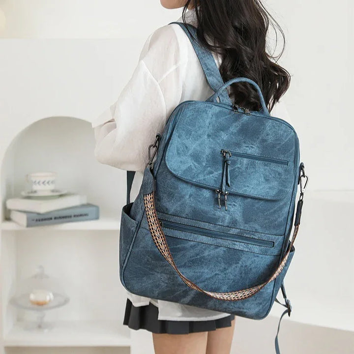 Woman wearing a stylish blue canvas backpack with multiple zippered pockets and adjustable straps