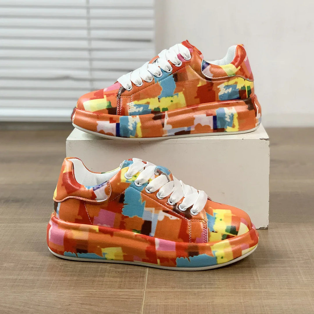 Pair of colorful abstract pattern sneakers with white laces on wooden floor and white display block