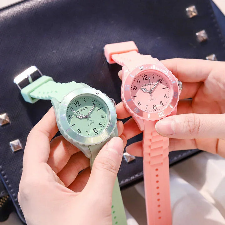 Hands holding pink and green Ulzzang quartz wristwatches with silicone straps over black studded bag