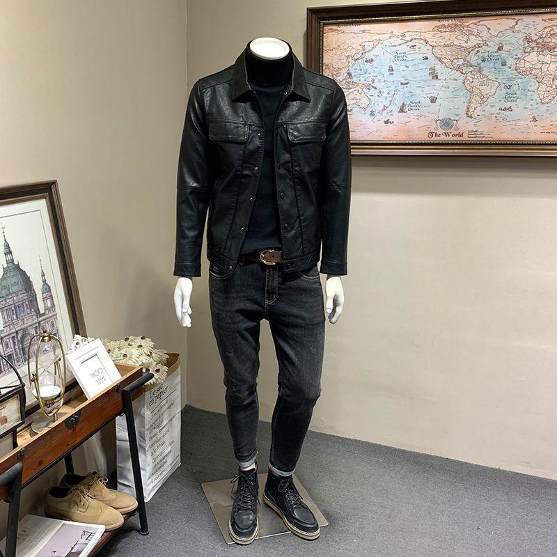 Mannequin dressed in black leather jacket, dark jeans, black boots in a room with world map and framed art