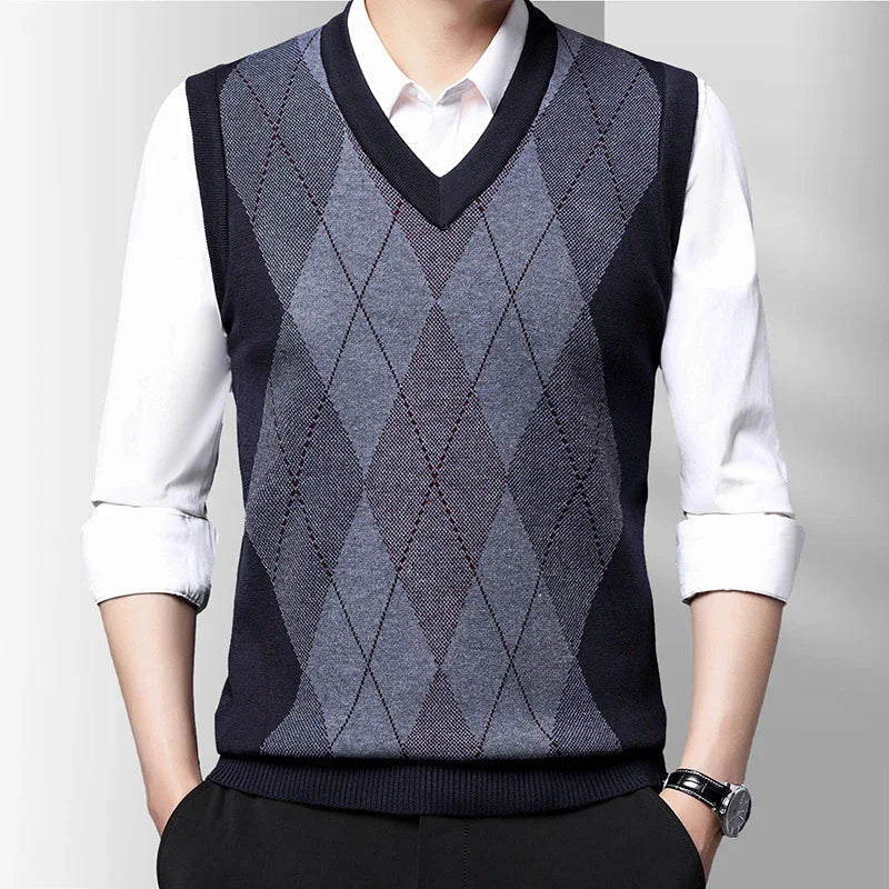 Man wearing navy blue and gray argyle knit vest over white shirt with rolled sleeves