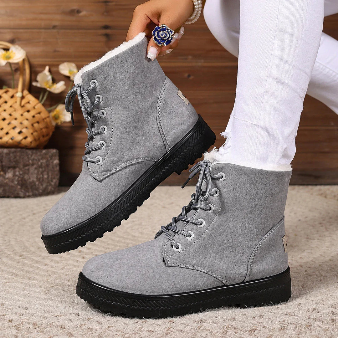 Gray suede winter boots with black soles and white fleece lining worn with white pants