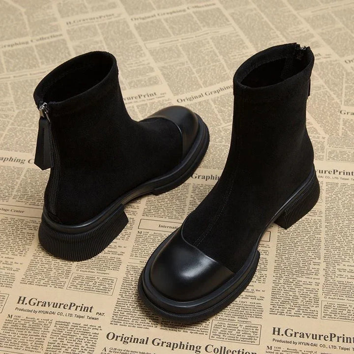Pair of black ankle boots with leather toe caps and chunky soles on newspaper background