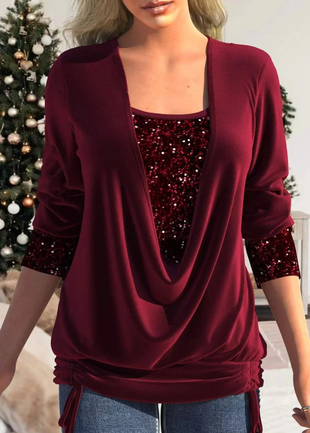 Woman wearing a burgundy layered top with sequined inner layer and long sleeves, Christmas tree background