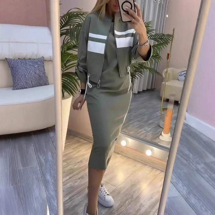 Woman in olive green sporty midi dress with white stripes taking mirror selfie indoors