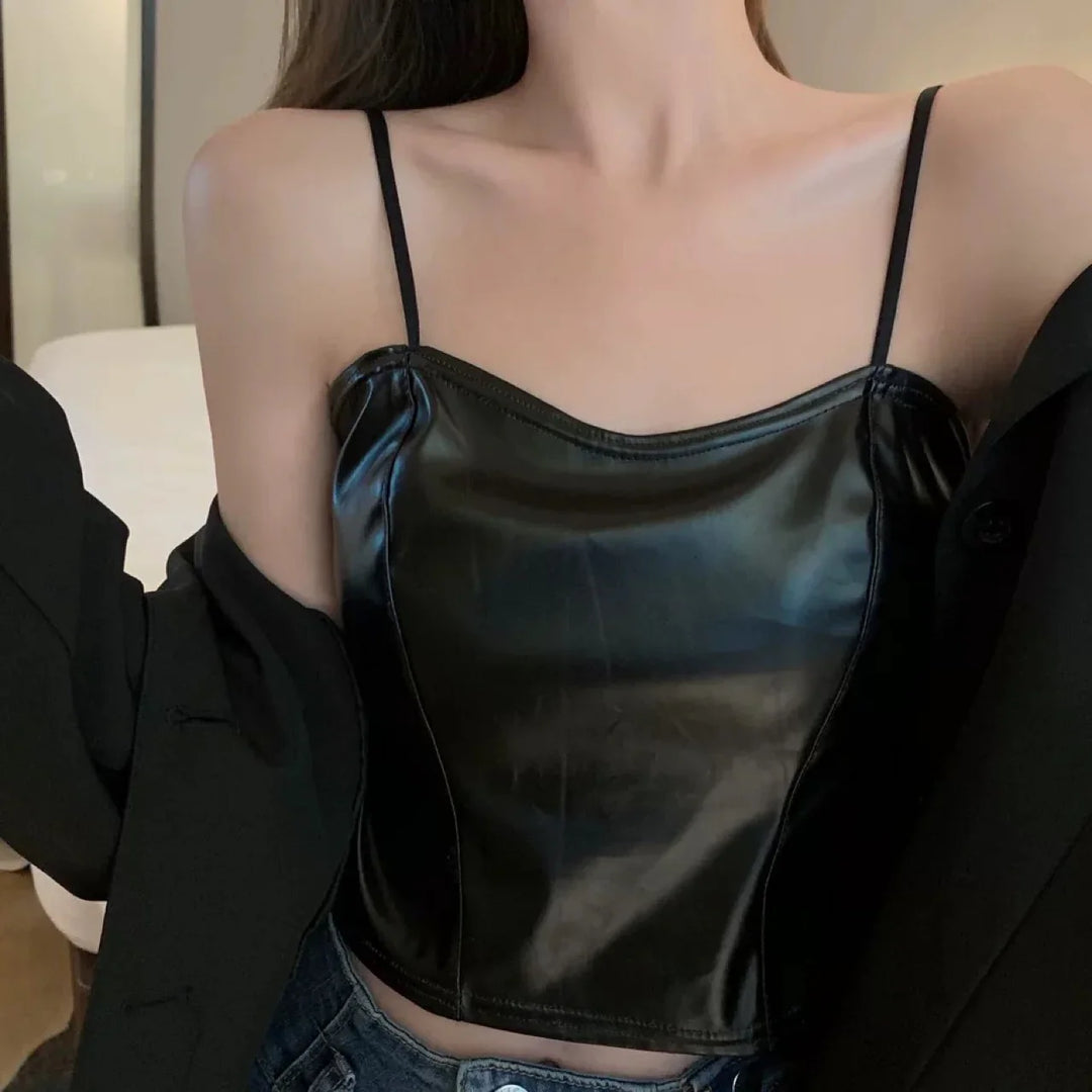 Close-up of woman wearing black faux leather spaghetti strap crop top with black jacket and denim jeans