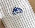 Close-up of white ribbed fabric with blue and white Falcon brand logo patch