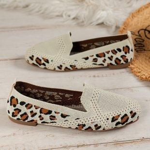 White perforated loafers with leopard print accents on wooden surface and woven rug