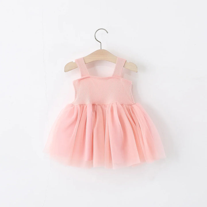 Pink toddler dress with ribbed bodice and tulle skirt hanging on wooden hanger