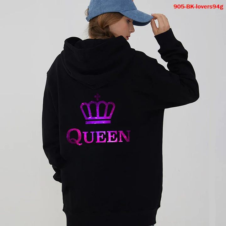 Woman wearing black hoodie with purple crown and Queen text, blue cap, gray background