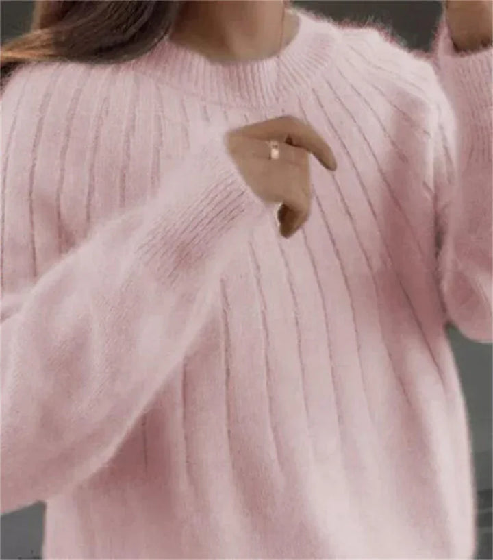 Close-up of a woman wearing a soft pink fuzzy ribbed sweater with long sleeves and a round neckline