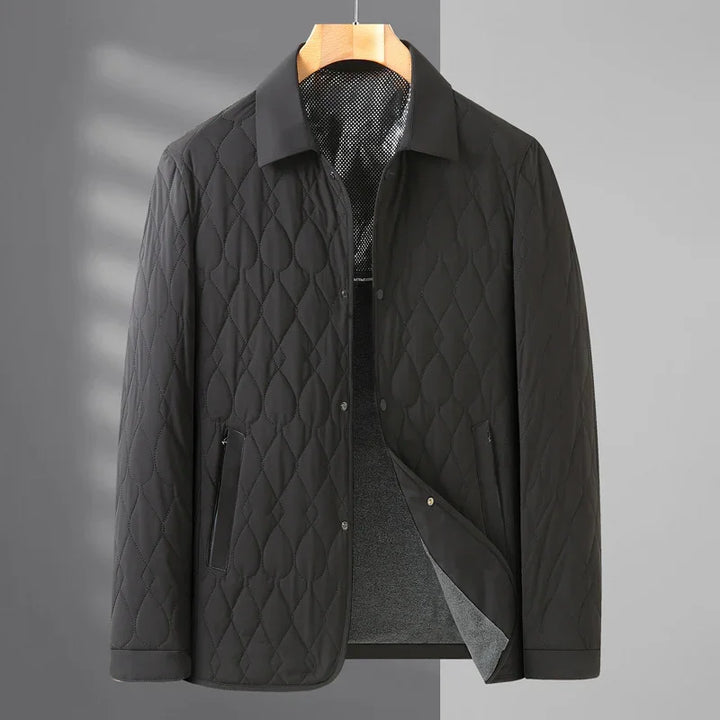 Black quilted men's jacket with diamond stitching and snap button closure on wooden hanger