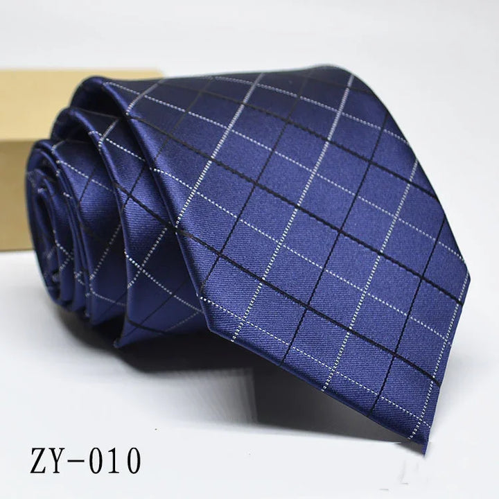 Rolled navy blue men's necktie with silver and black grid pattern on white background