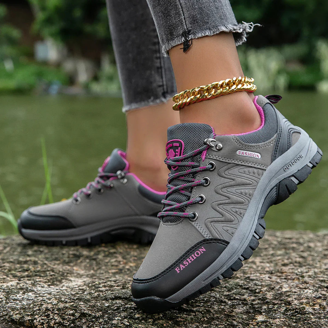 gray and pink outdoor hiking shoes worn with gold anklet and frayed black jeans by a pond