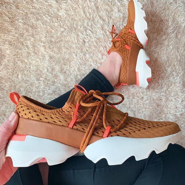 Brown mesh sneakers with white chunky soles and orange accents on a beige carpet