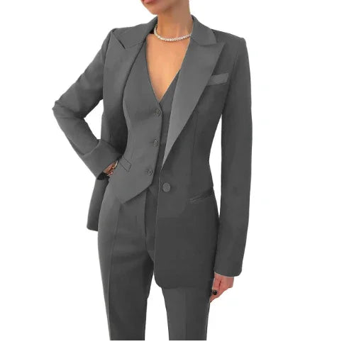 Woman wearing a sleek dark gray tailored pantsuit with blazer and vest, accessorized with a pearl necklace