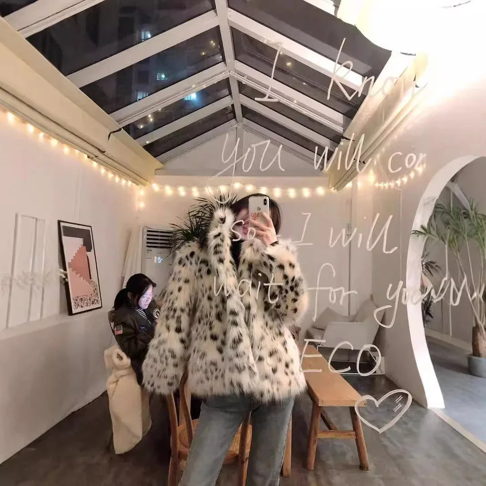 Person in spotted faux fur coat taking mirror selfie in cozy room with string lights and indoor plants