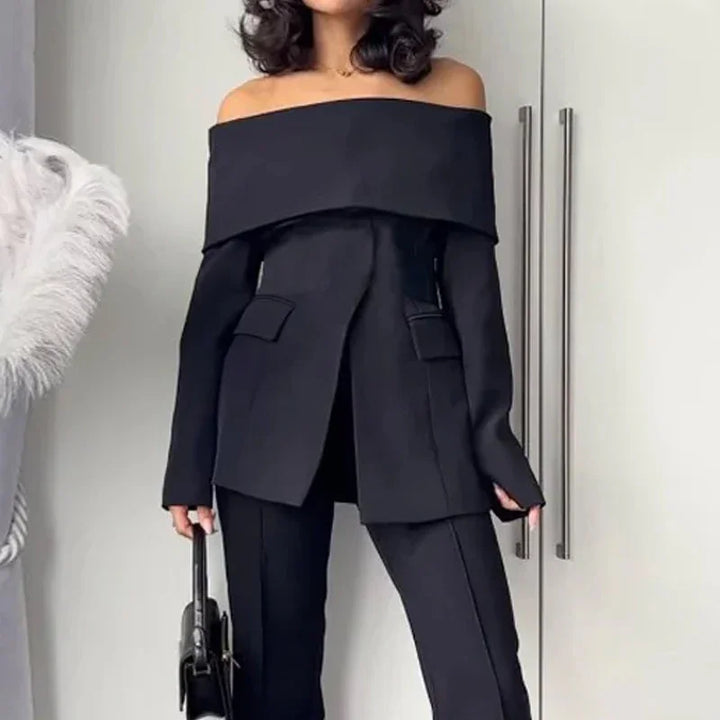 Woman wearing a stylish black off-shoulder blazer with matching pants holding a black handbag
