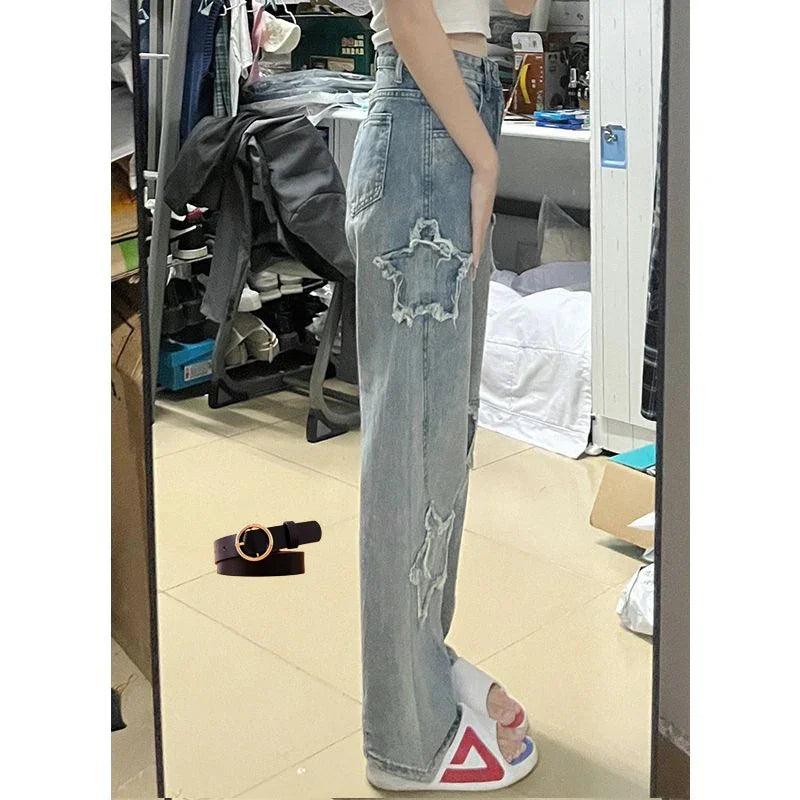 Woman wearing light blue distressed star patch jeans and white slide sandals standing in room mirror