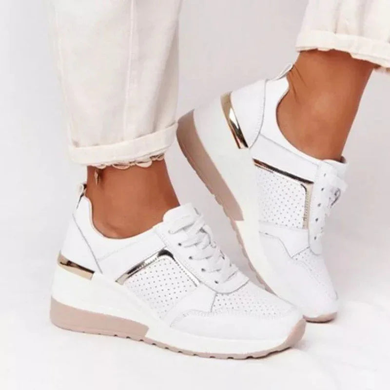 White perforated platform sneakers with metallic gold accents worn with rolled-up white pants