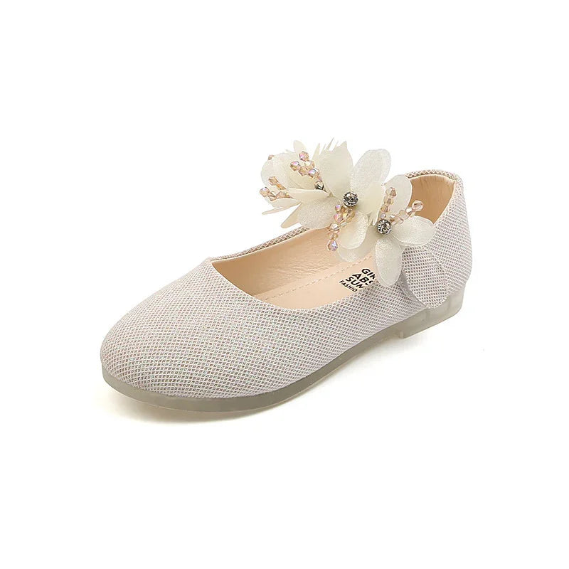White girls flat shoe with textured fabric and decorative floral embellishment on strap