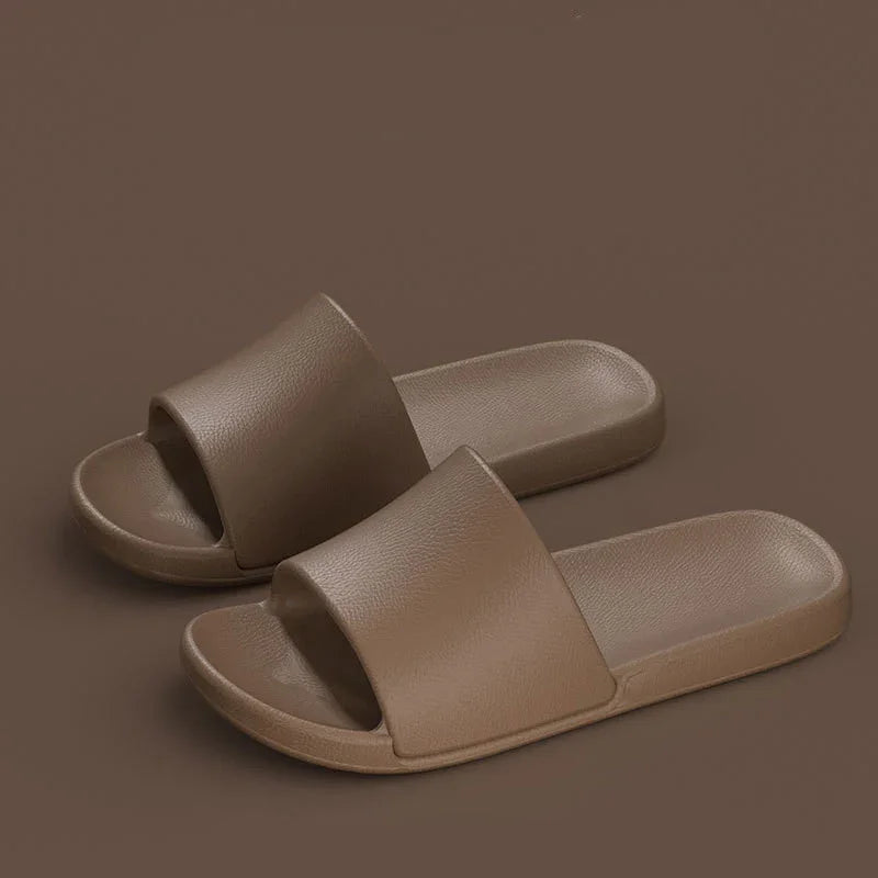 Pair of brown slide sandals with textured surface on matching brown background