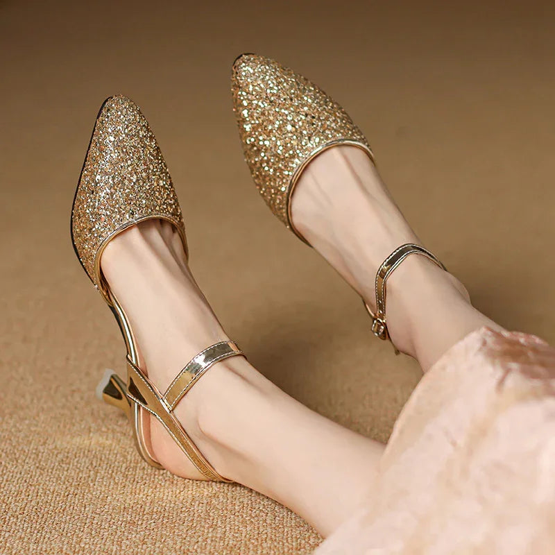 Women's sparkling gold glitter pointed-toe slingback heels with ankle straps on beige carpet
