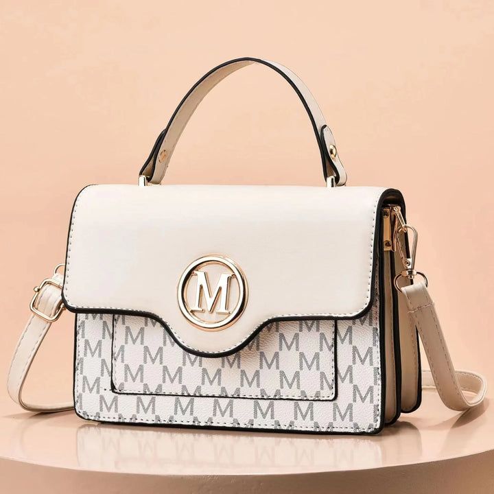 Beige and white handbag with gold M logo, patterned front, top handle and detachable shoulder strap