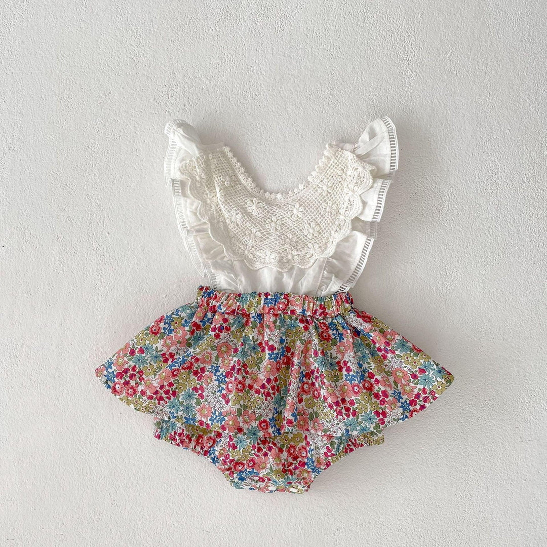 Baby romper with white ruffled crochet top and floral patterned skirt on white background
