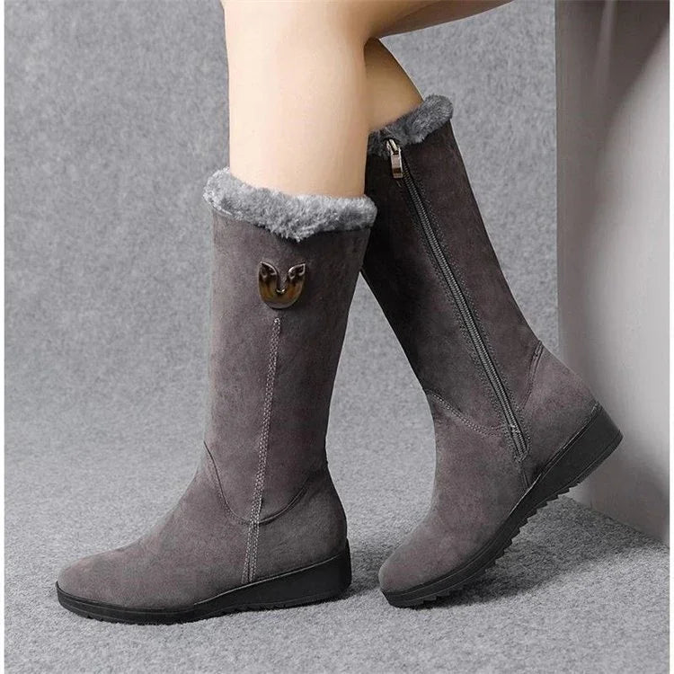 Gray suede winter boots with gray fur lining and side zipper, worn on model against gray background